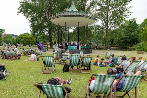 People enjoy live music in a park bandstand.