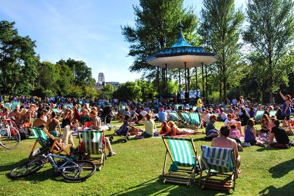 Crowd enjoying a sunny day in a park with a bandstand; Nottingham, UK
