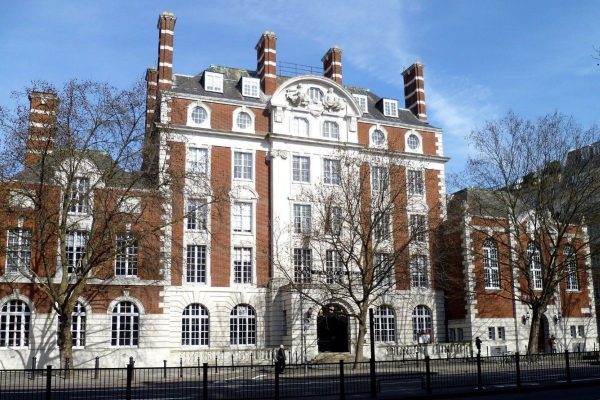 Large brick and white building with chimneys under a blue sky.